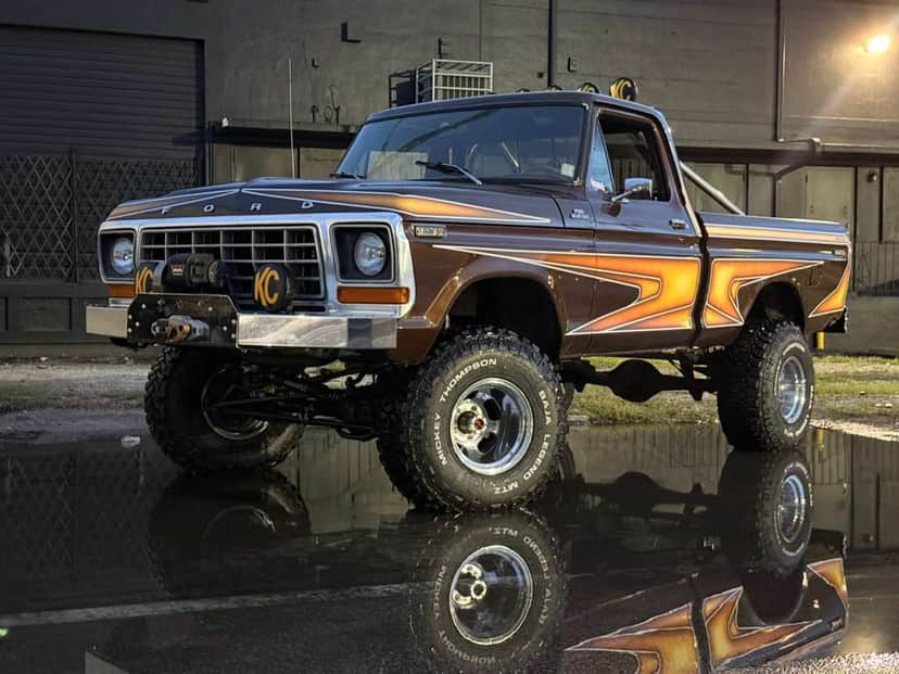 Brownie, a lifted brown 1978 Ford F-150 with KC lights, reflected in wet asphalt at dusk