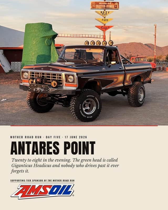 Designed sheet, Antares Point: Brownie in evening light in front of a giant green head sculpture and a stack of hand-painted roadside signs.