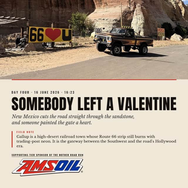 Designed sheet, Somebody Left A Valentine: Brownie on the roadside below red sandstone cliffs, beside a yellow gate painted with a heart between the numerals sixty-six.
